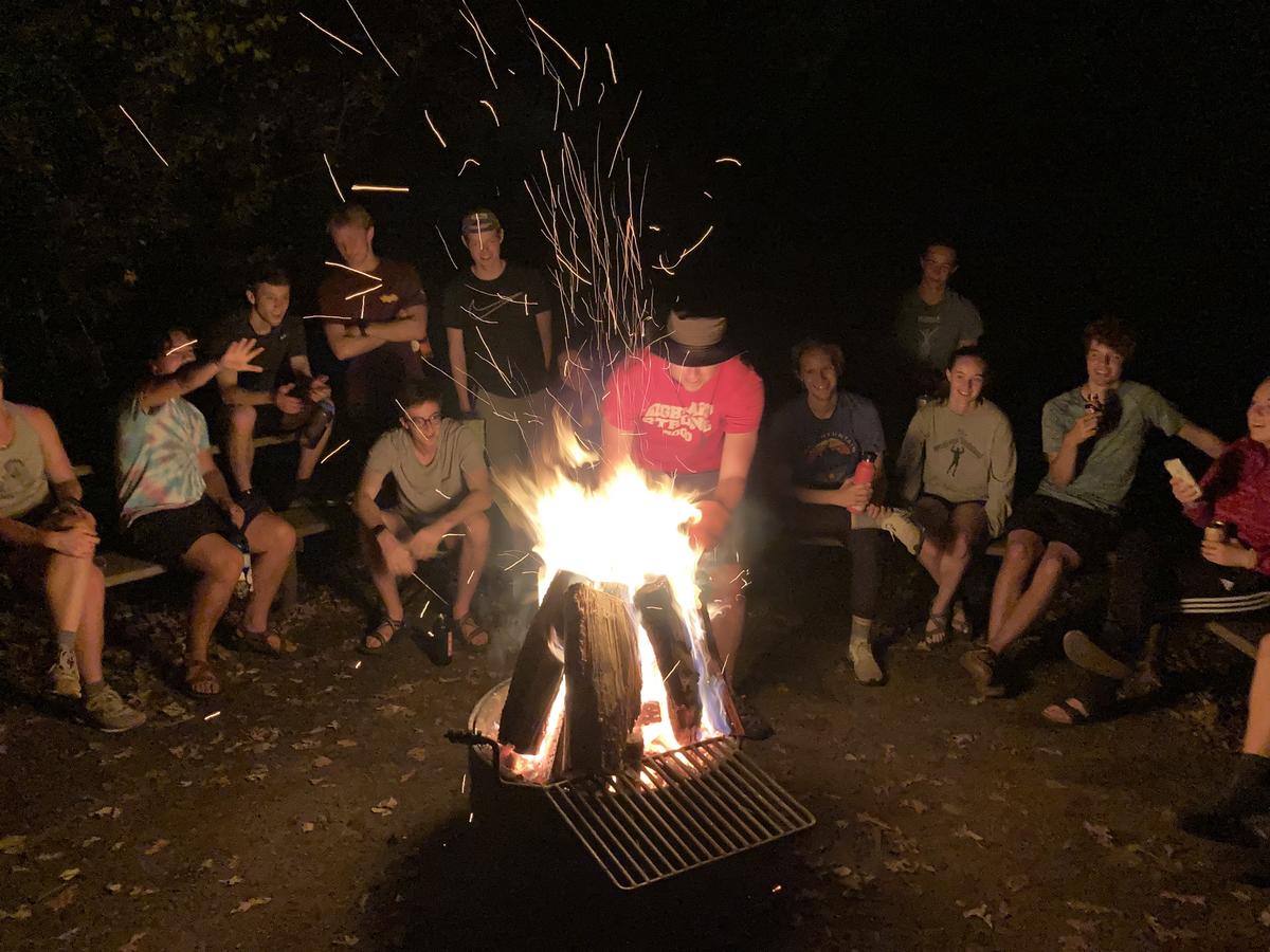 Picture of a bonfire with members around it on team camping trip